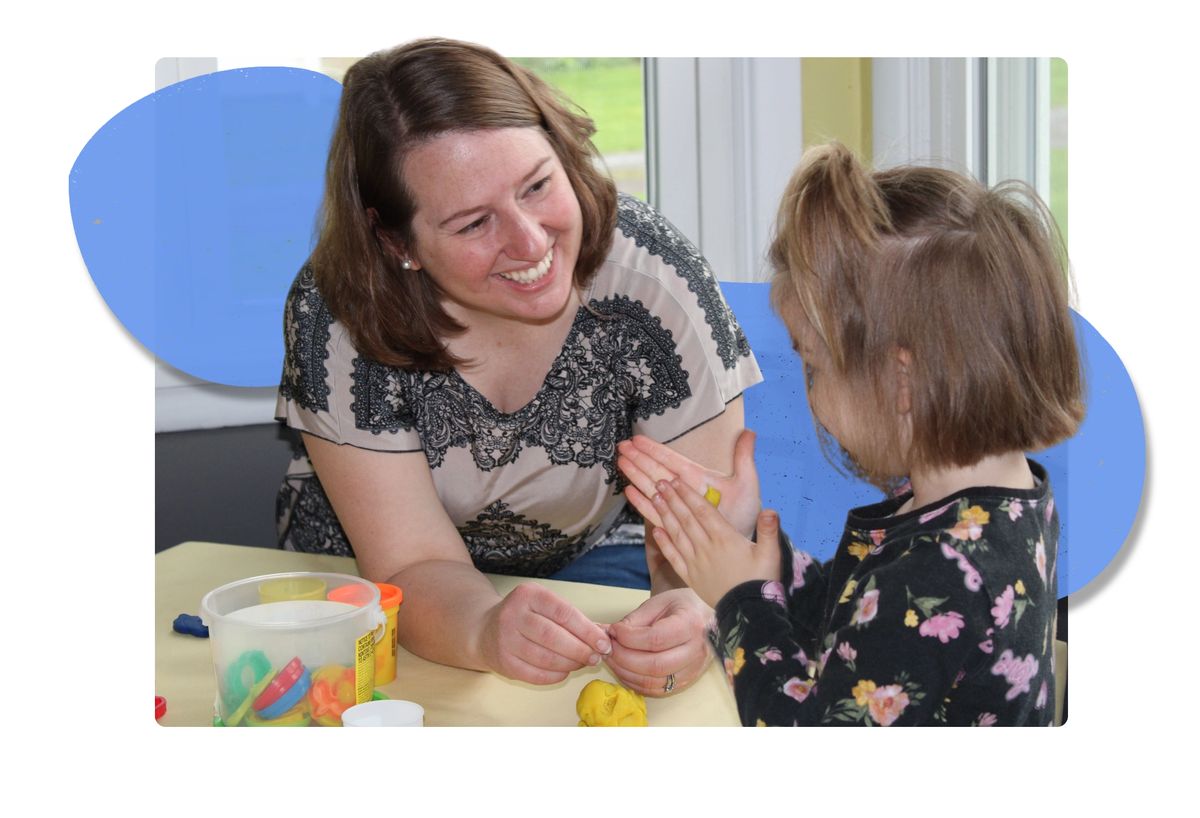 A therapist playing with a young child at a table